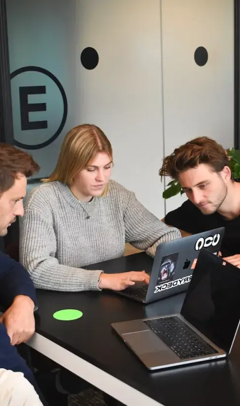 Team members collaborating on a laptop in an office meeting
